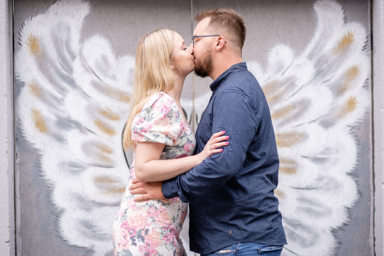 Sesja narzeczeńska na tle malowanej ściany ze skrzydłami anioła